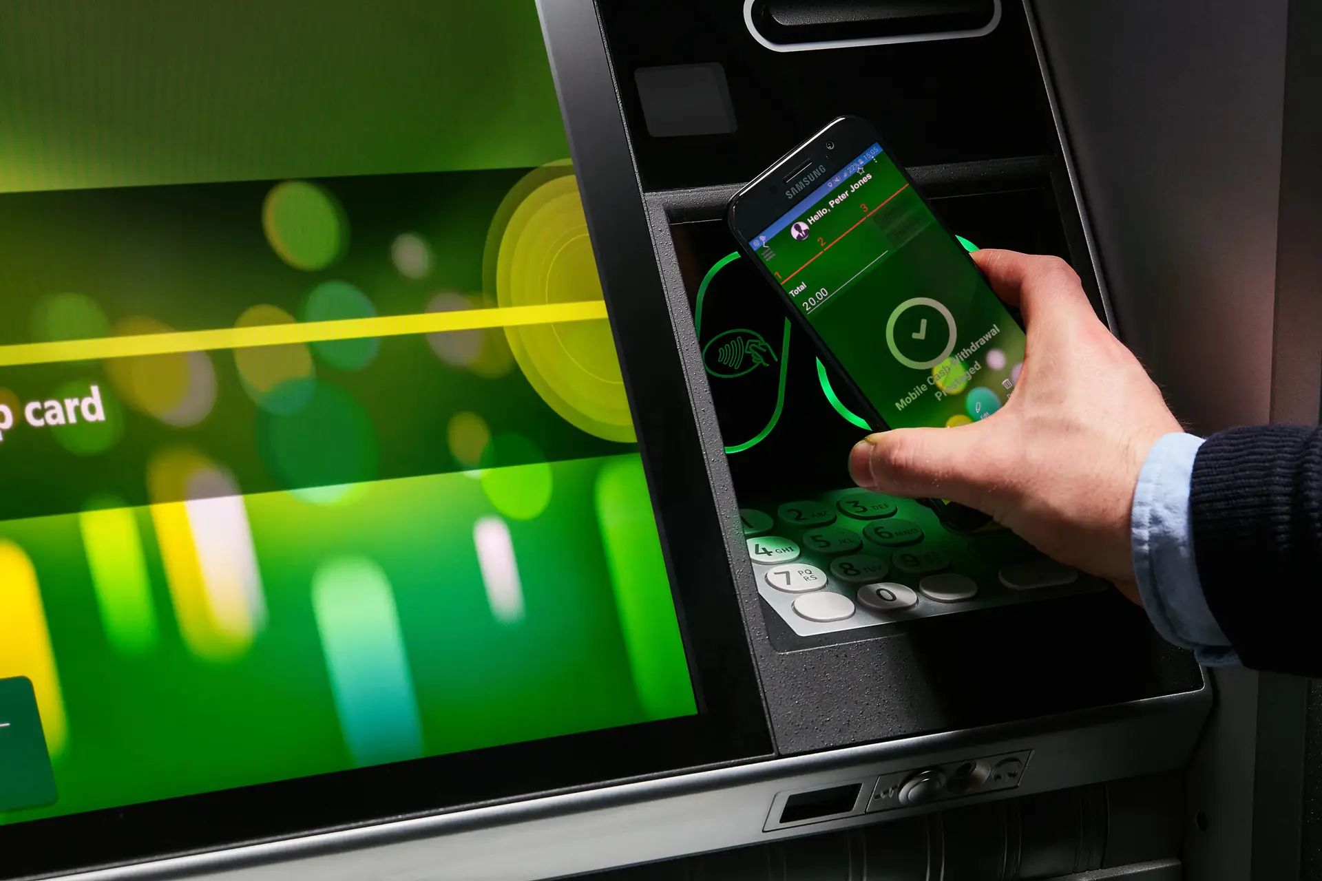 customer holding phone up to ATM, represents digital banking services available through Edge One